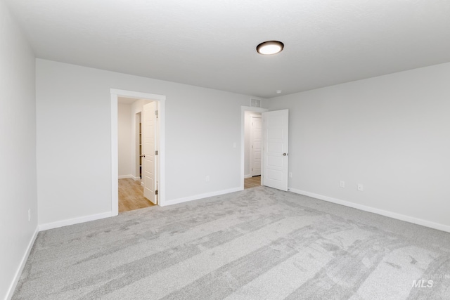 carpeted spare room featuring visible vents and baseboards