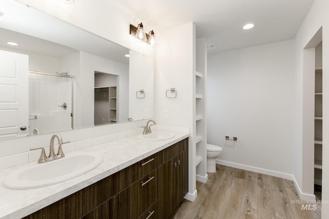 full bathroom with a stall shower, a sink, toilet, and wood finished floors