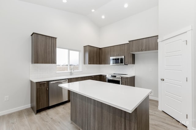 kitchen featuring dark brown cabinetry, high vaulted ceiling, stainless steel appliances, and light countertops