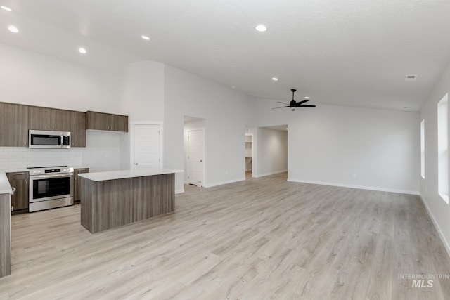 kitchen with a center island, light countertops, appliances with stainless steel finishes, open floor plan, and ceiling fan