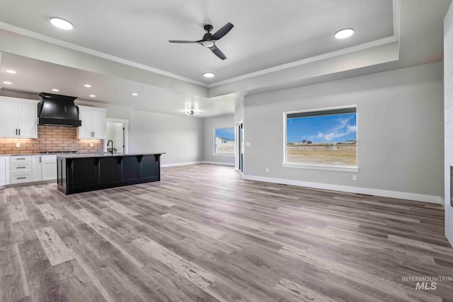 unfurnished living room featuring sink, crown molding, light hardwood / wood-style floors, and ceiling fan