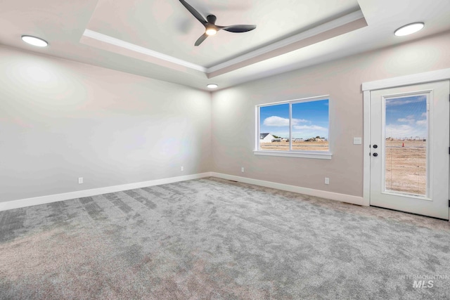 unfurnished room with ceiling fan, carpet flooring, and a tray ceiling