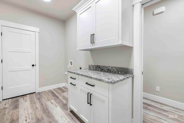 kitchen featuring light hardwood / wood-style floors, white cabinets, and light stone counters