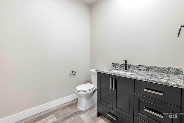 bathroom with toilet, hardwood / wood-style floors, and vanity