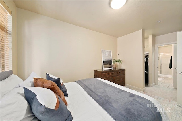 bedroom with connected bathroom, light tile patterned floors, and a closet