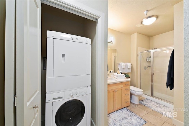 washroom featuring sink, light tile patterned floors, and stacked washer and dryer