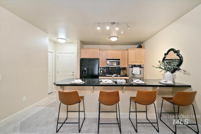 kitchen featuring light brown cabinets, sink, tasteful backsplash, a kitchen bar, and stainless steel appliances