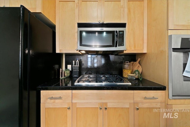 kitchen with light brown cabinets, decorative backsplash, and appliances with stainless steel finishes