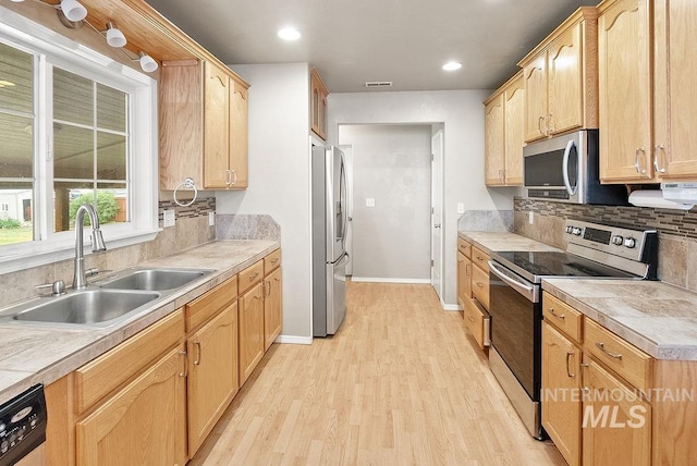 720 E Main St, Jerome, ID 83338 - kitchen with stainless steel appliances, a sink, light wood-type flooring, light brown cabinets, and decorative backsplash