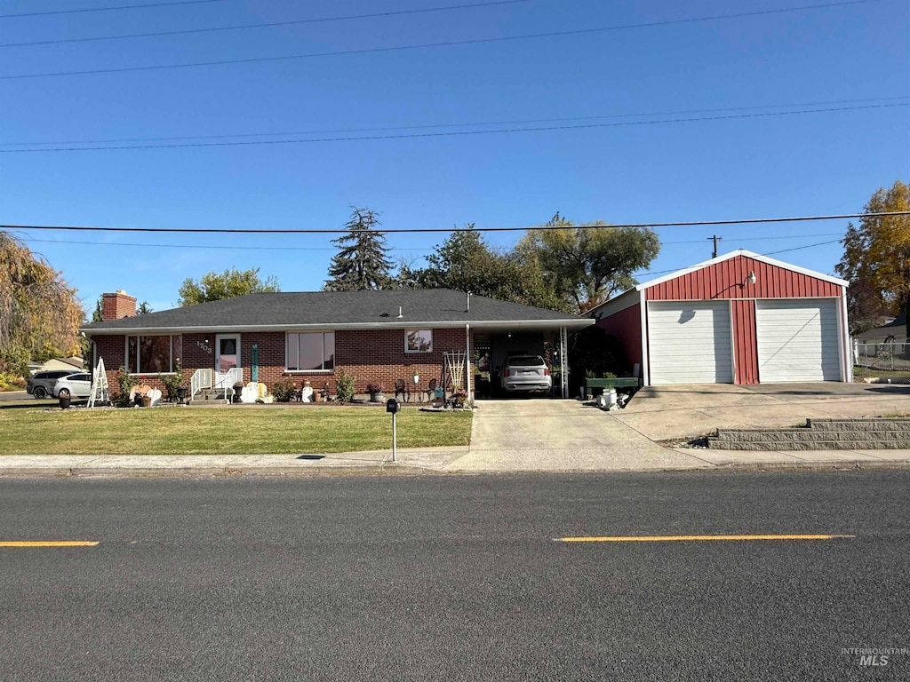 ranch-style home featuring a garage, an outbuilding, a carport, and a front lawn