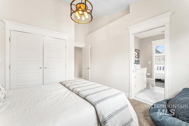 carpeted bedroom with a closet, baseboards, and ensuite bathroom
