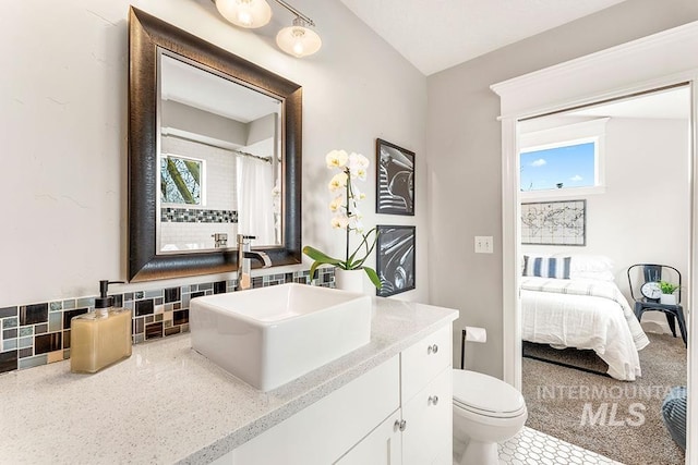 ensuite bathroom with connected bathroom, decorative backsplash, vanity, a shower with curtain, and toilet