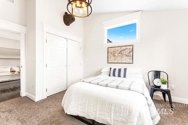 carpeted bedroom with a closet, baseboards, and an inviting chandelier