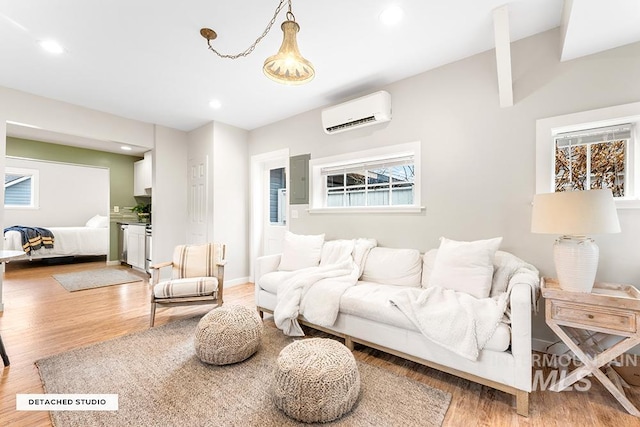 living area featuring electric panel, light wood-style floors, a wall mounted AC, and recessed lighting