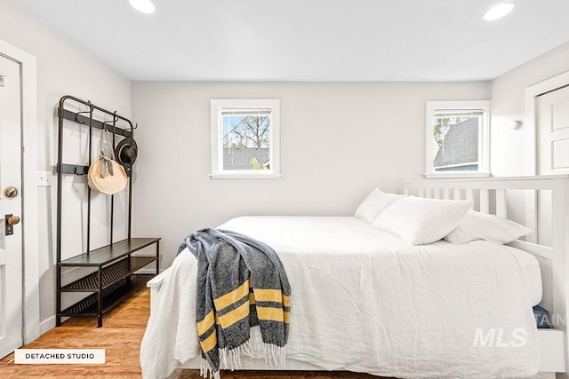 bedroom with recessed lighting, wood finished floors, and multiple windows