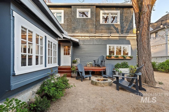 back of property with a fire pit, a patio, and mansard roof
