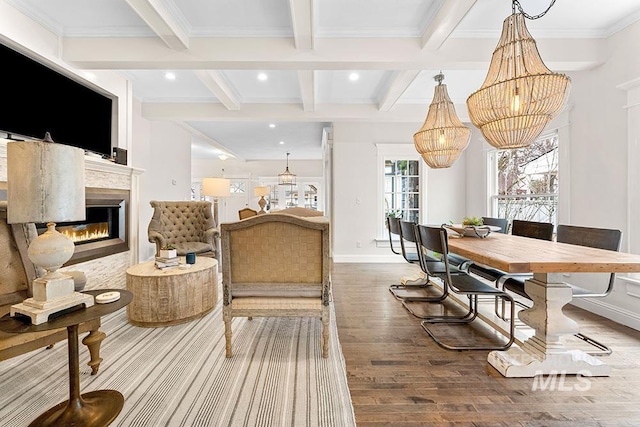 interior space featuring beam ceiling, baseboards, a glass covered fireplace, a notable chandelier, and wood finished floors