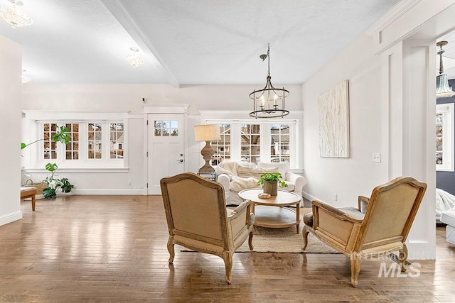 sitting room with wood-type flooring, a chandelier, and baseboards