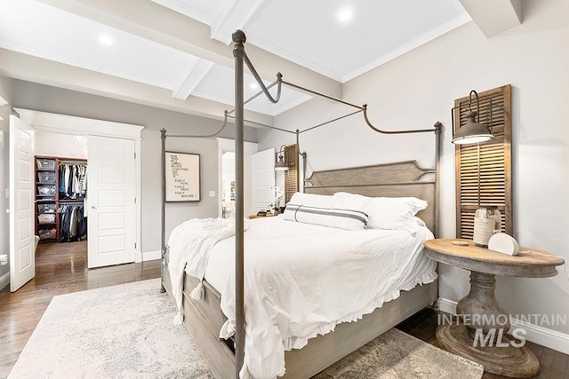 bedroom with wood finished floors, beam ceiling, baseboards, and ornamental molding