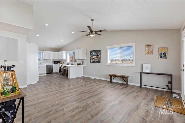 living room featuring a ceiling fan, vaulted ceiling, a healthy amount of sunlight, and light wood-style floors