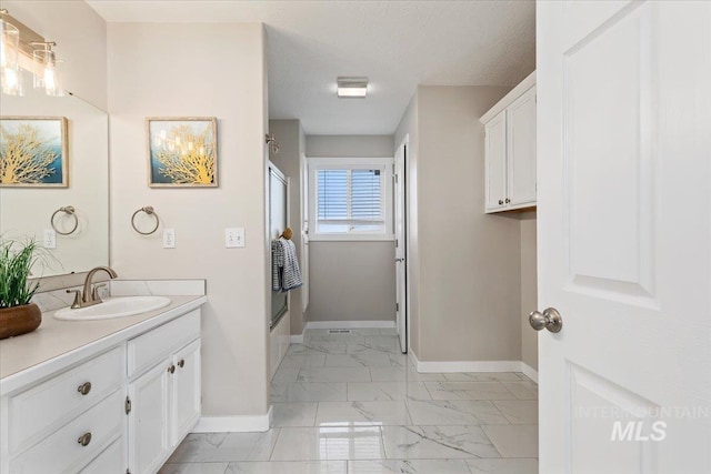 bathroom with baseboards, a textured ceiling, marble finish floor, and vanity
