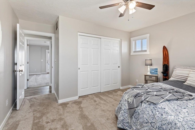 bedroom with baseboards, light carpet, a textured ceiling, and a closet