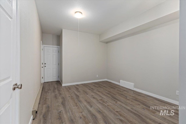 spare room featuring visible vents, wood finished floors, and baseboards