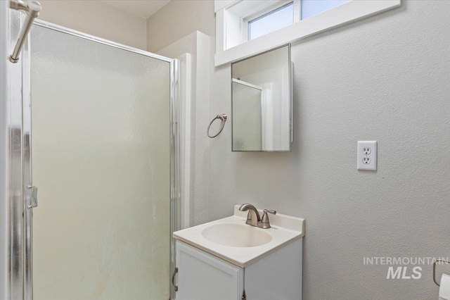 bathroom with a shower stall, vanity, and a textured wall