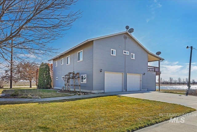 view of side of property with concrete driveway, an attached garage, and a lawn