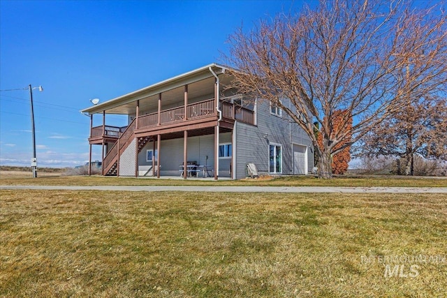 back of house featuring a garage, a lawn, a deck, and stairway