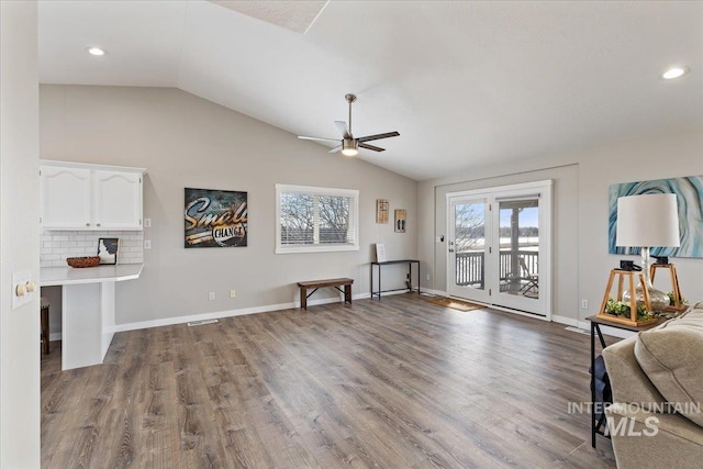living area with baseboards, lofted ceiling, wood finished floors, and a ceiling fan