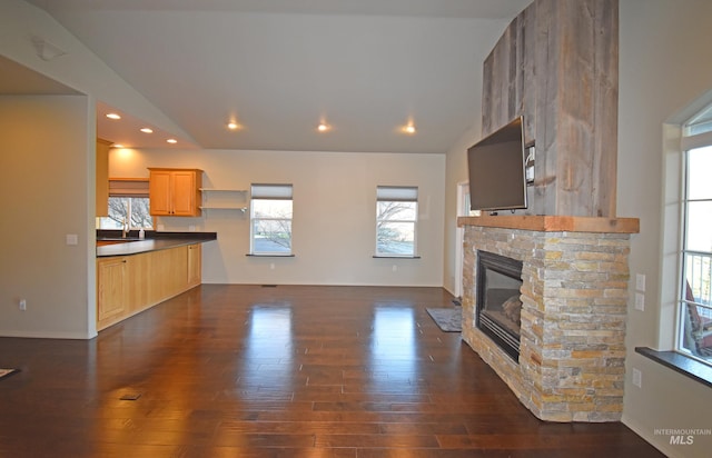 unfurnished living room with a fireplace, sink, dark wood-type flooring, and lofted ceiling