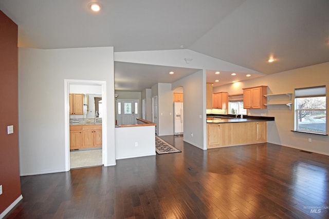 kitchen featuring lofted ceiling, white refrigerator with ice dispenser, kitchen peninsula, dark hardwood / wood-style floors, and light brown cabinets