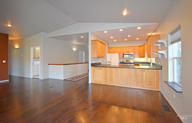 kitchen featuring washer / dryer, lofted ceiling, dark wood-type flooring, stainless steel appliances, and light brown cabinets