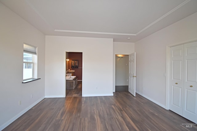 unfurnished bedroom featuring a closet, dark hardwood / wood-style floors, and ensuite bath