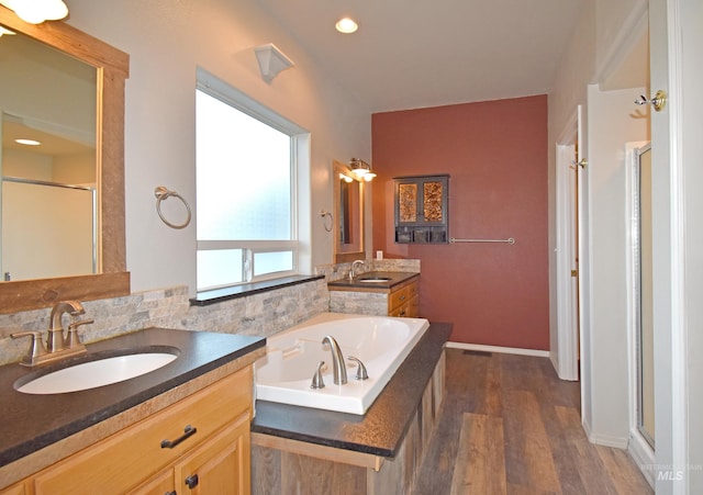 bathroom with wood-type flooring, vanity, and plus walk in shower