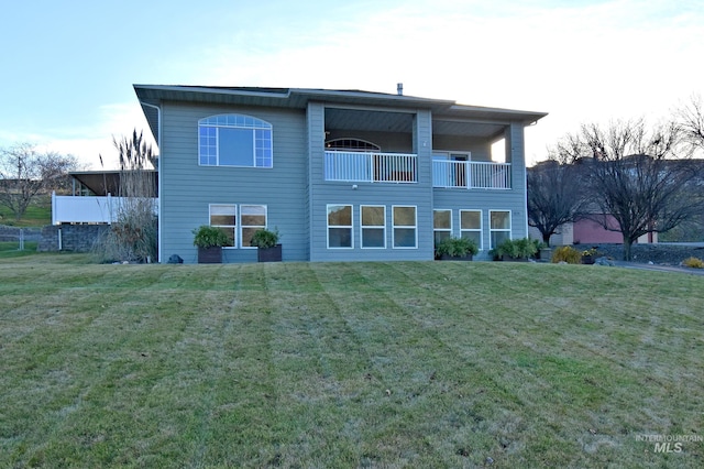 back of property featuring a balcony and a lawn