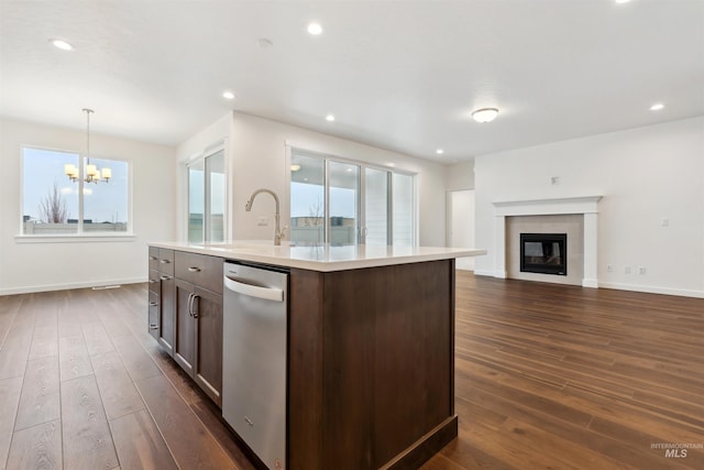 kitchen with a tiled fireplace, a sink, open floor plan, dark wood finished floors, and light countertops