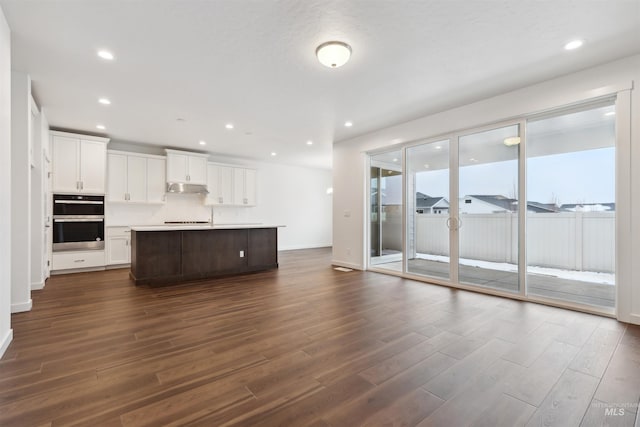 unfurnished living room with recessed lighting, baseboards, and dark wood-style flooring