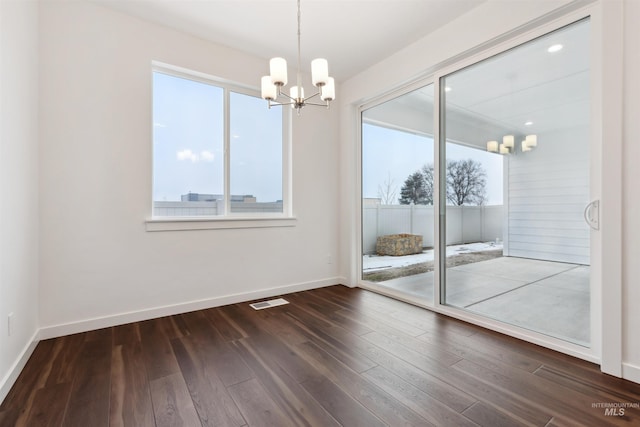 spare room with an inviting chandelier, baseboards, dark wood-style flooring, and visible vents