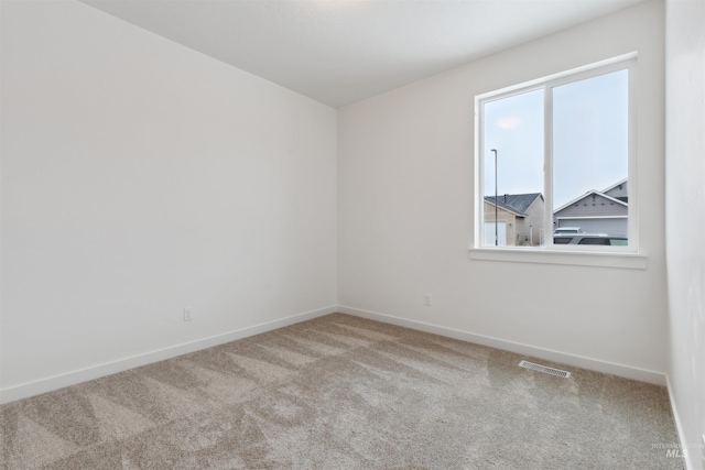 carpeted spare room with visible vents and baseboards