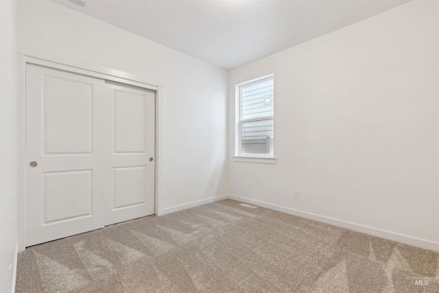 unfurnished bedroom featuring a closet, visible vents, baseboards, and carpet floors