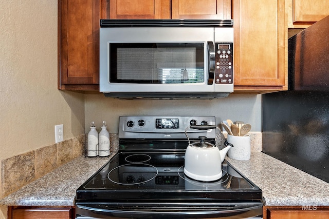 kitchen with black range with electric cooktop and light stone countertops