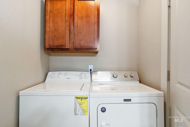 clothes washing area with washing machine and dryer and cabinets