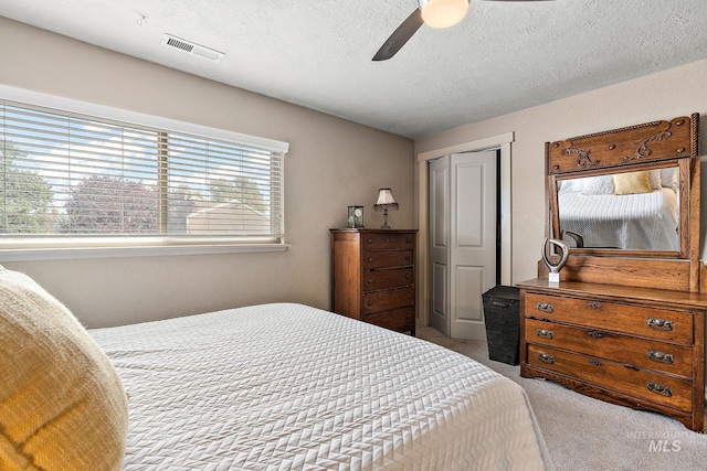 carpeted bedroom featuring multiple windows, a textured ceiling, a closet, and ceiling fan