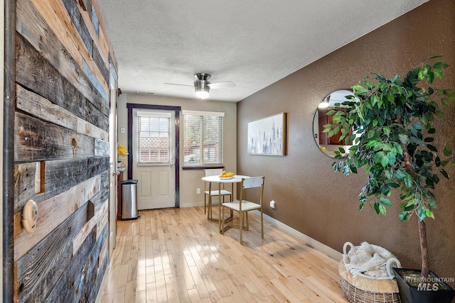 dining space with light hardwood / wood-style floors, a textured ceiling, and ceiling fan