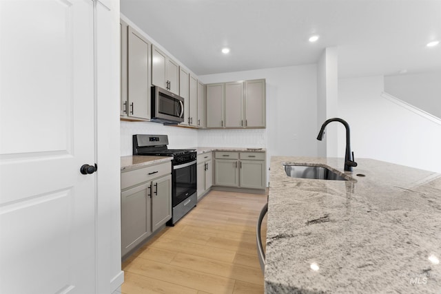 690 N Tessa Ave, Meridian, ID 83642 - kitchen with stainless steel appliances, a sink, gray cabinets, light stone counters, and light wood finished floors
