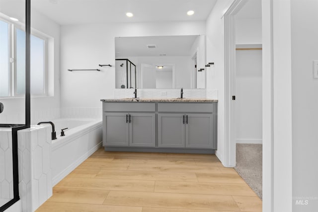 690 N Tessa Ave, Meridian, ID 83642 - full bathroom featuring wood finished floors, double vanity, a stall shower, a bath, and recessed lighting