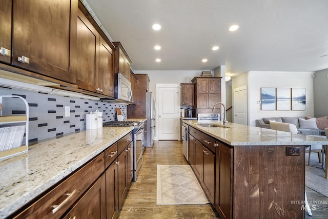 2858 Sunray Loop, Twin Falls, ID 83301 - kitchen featuring appliances with stainless steel finishes, a sink, wood finished floors, an island with sink, and light stone countertops