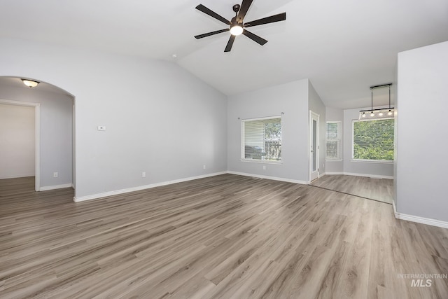 1030 Caswell Ave W, Twin Falls, ID 83301 - unfurnished living room featuring a ceiling fan, arched walkways, wood finished floors, and vaulted ceiling